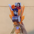 Bouquet made of candy and snacks shaped like a bouquet with a person holding it outdoors.