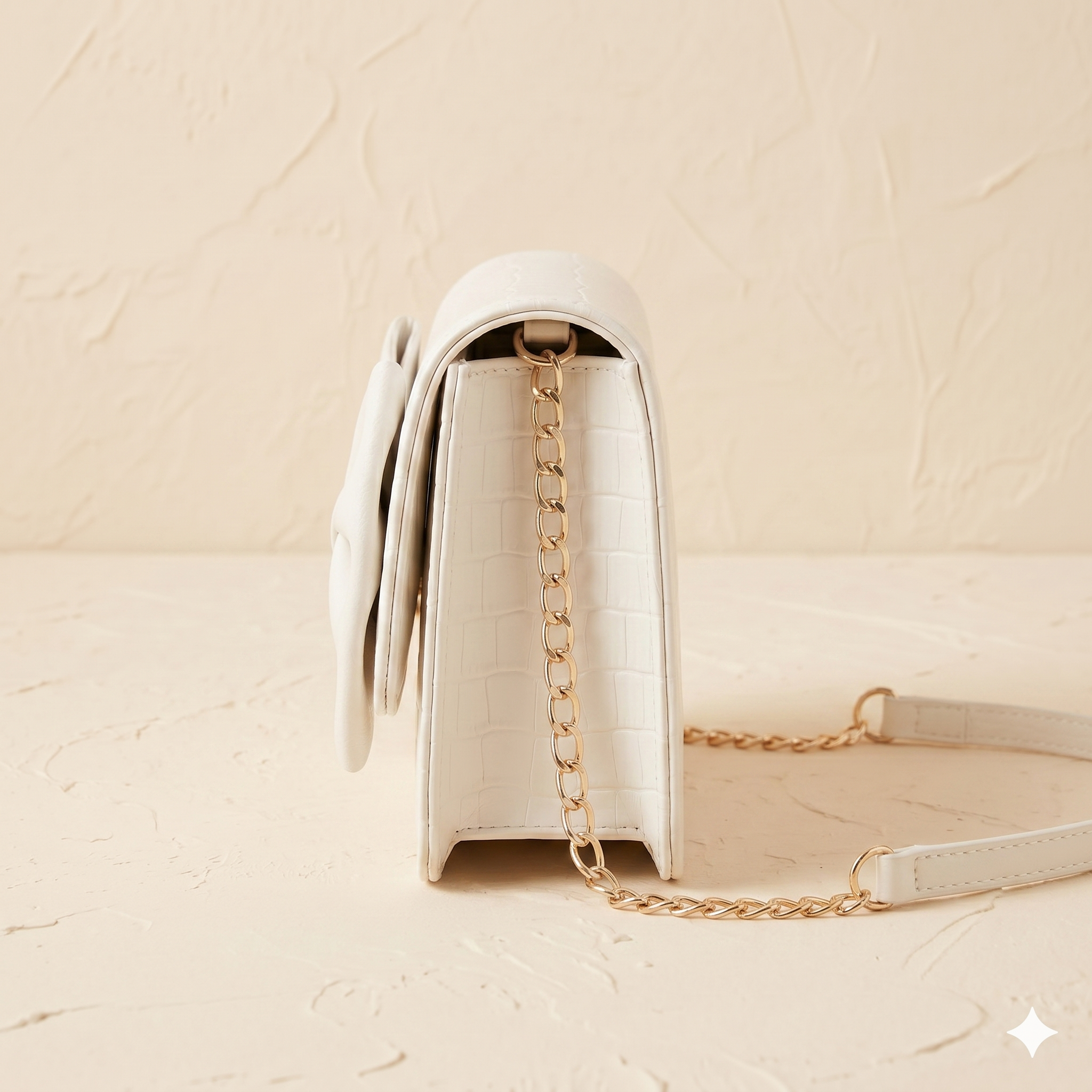 White handbag with gold chain strap on a beige background