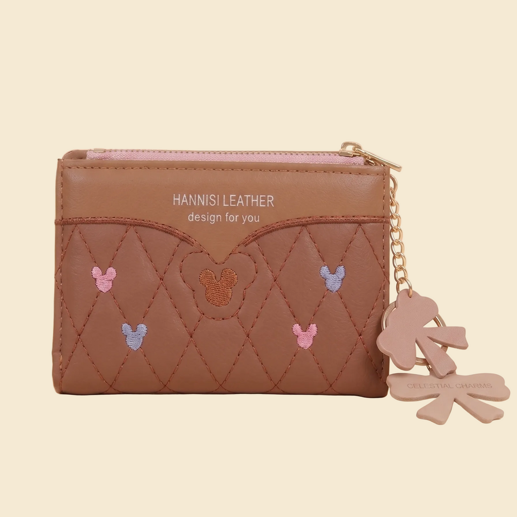 Brown leather wallet with embroidered designs and a keychain on a beige background