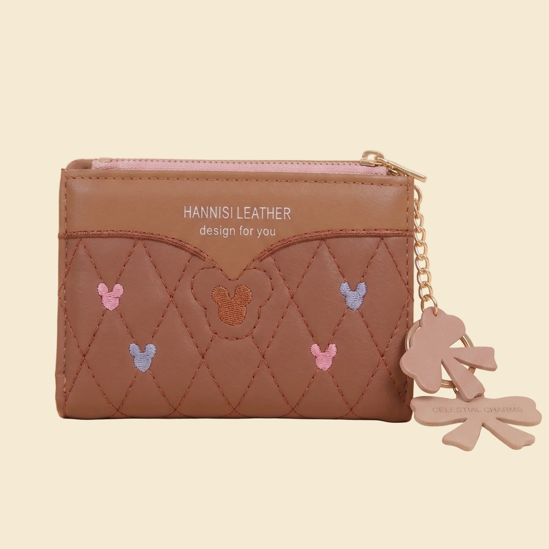Brown leather wallet with embroidered designs and a keychain on a beige background